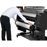 Person operating a large printer with a roll of paper