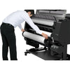 Person operating a large printer with a roll of paper